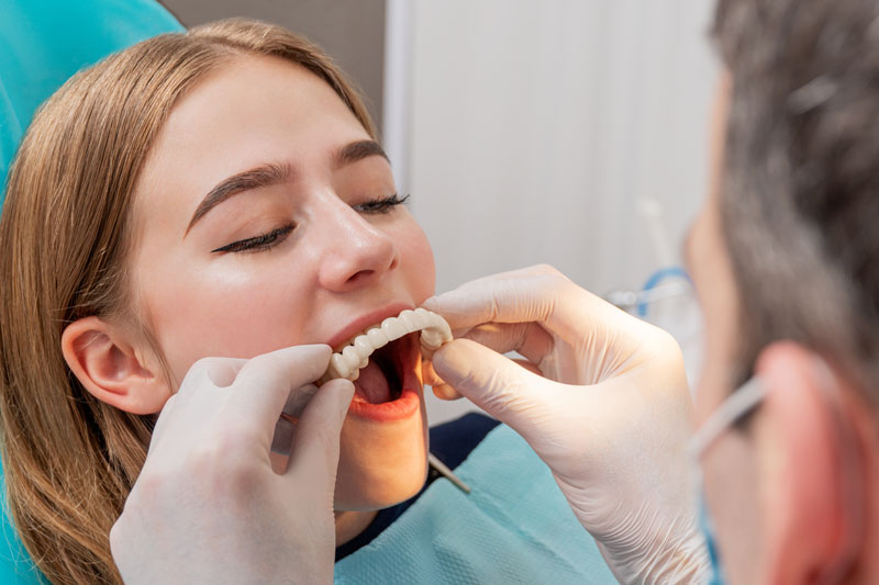 a picture of a patient getting her temporary prosthesis placed by the periodontist during her Teeth-in-a-Day procedure.