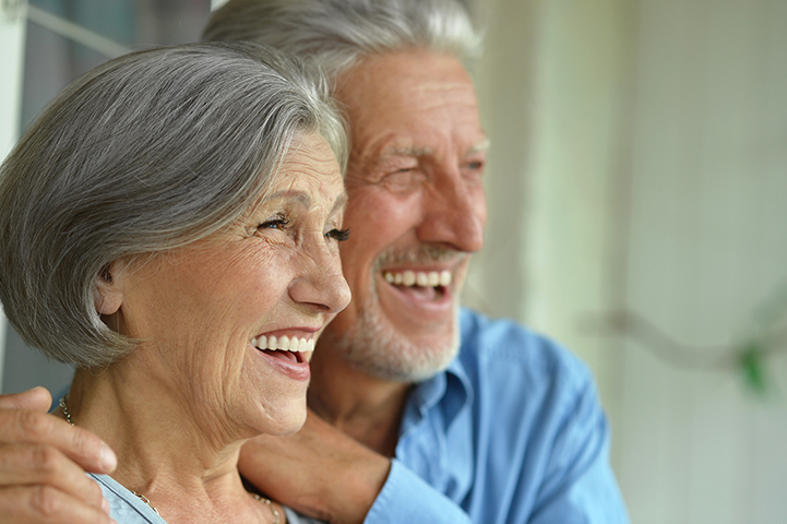 An image of a couple smiling with full mouth dental implants.