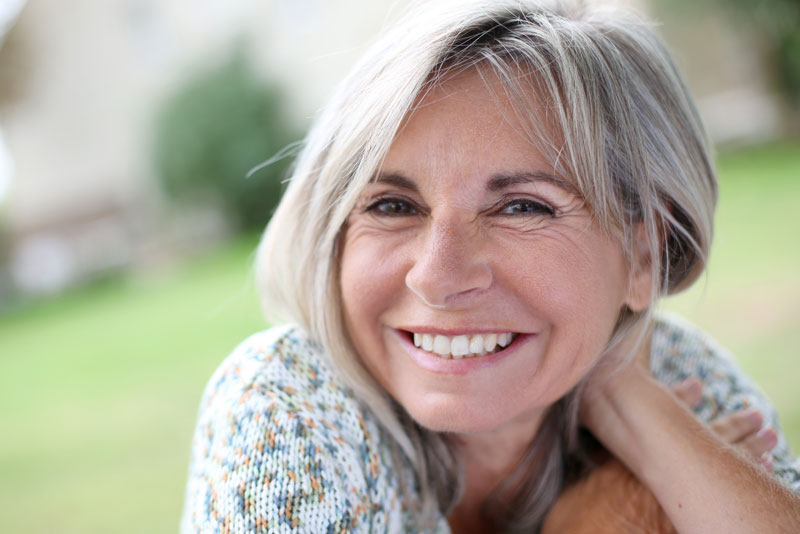 An image of a woman with dental implants smiling.