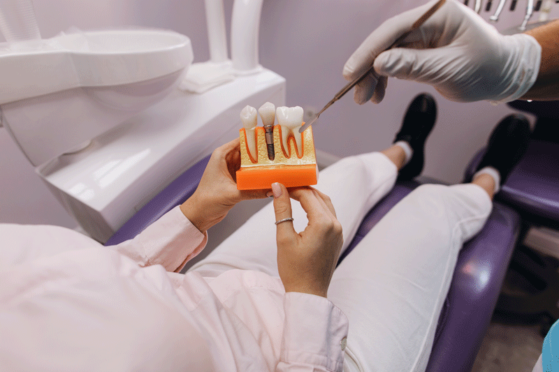 Patient in chair holding a dental implant model with thew doctor giving information.